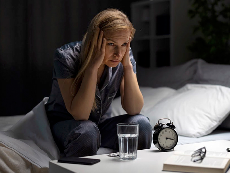 Woman by her bed side with her head in her hands