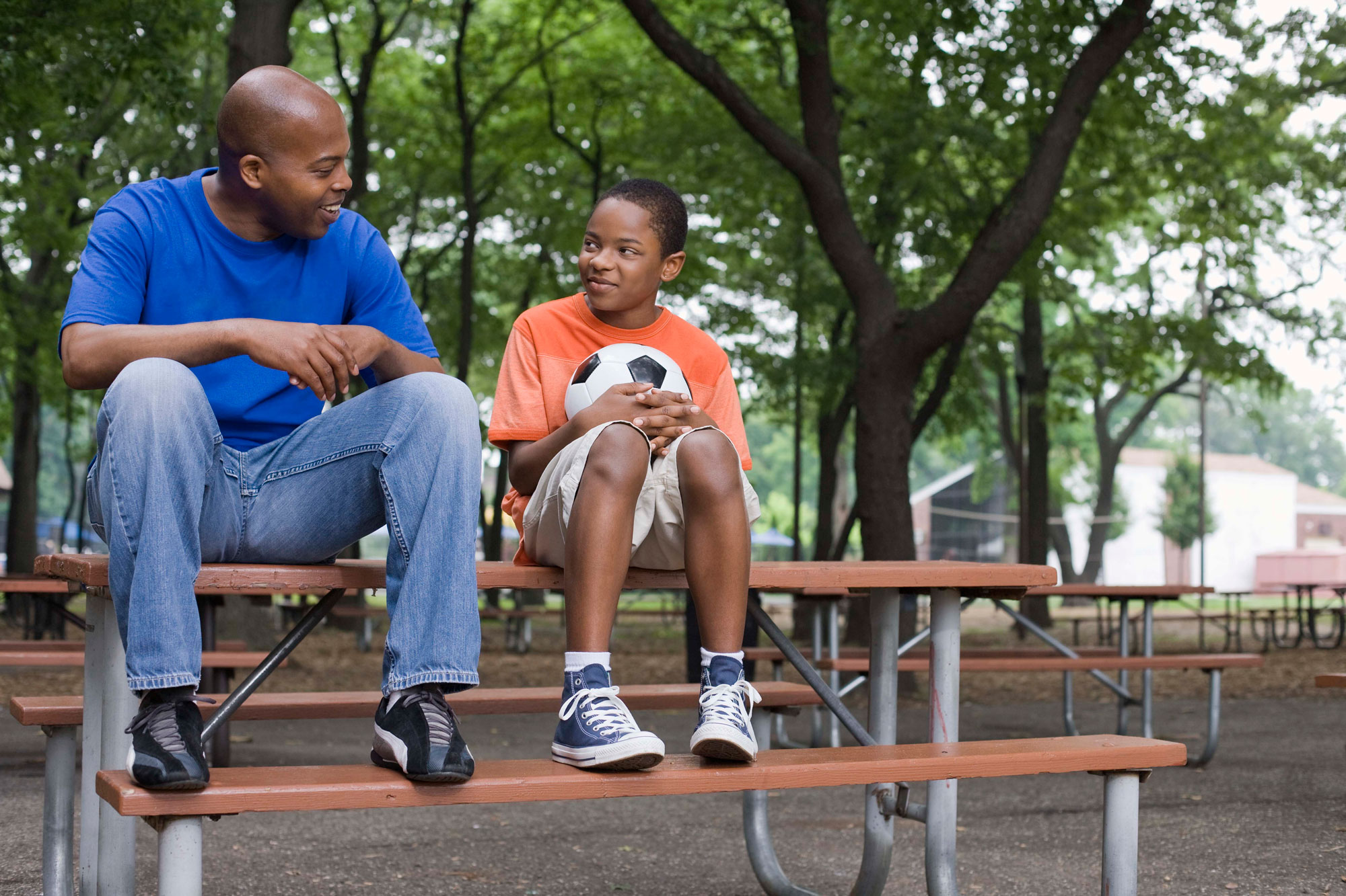 Man talking to younger child on picnic bench