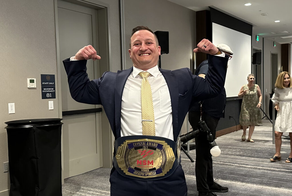 Joe Spinelli flexing with his custom award wrestling belt